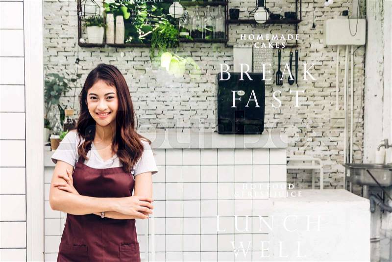 Portrait of woman small business owner smiling and standing with crossed arms outside the cafe or coffee shop.woman barista standing at cafe, stock photo