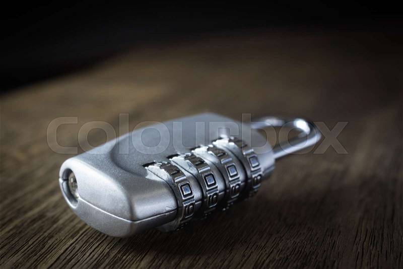 Selective focus on 4 digits code number of silver combination pad lock on wooden table, dark tone dim light background. Data protection, key management, password ..., stock photo