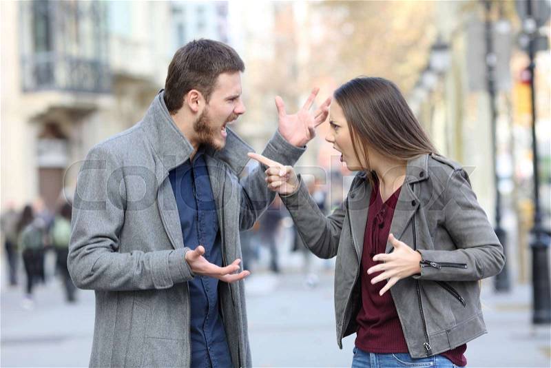 Angry couple arguing in the middle of a city street, stock photo