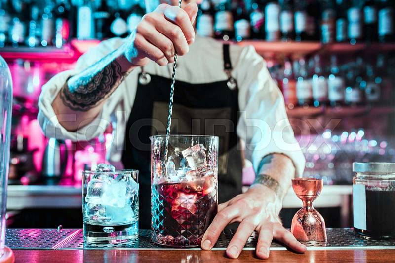 Expert barman is making cocktail at night club or bar. Glass of fiery cocktail on the bar counter against the background of bartenders hands with fire. Barman day ..., stock photo