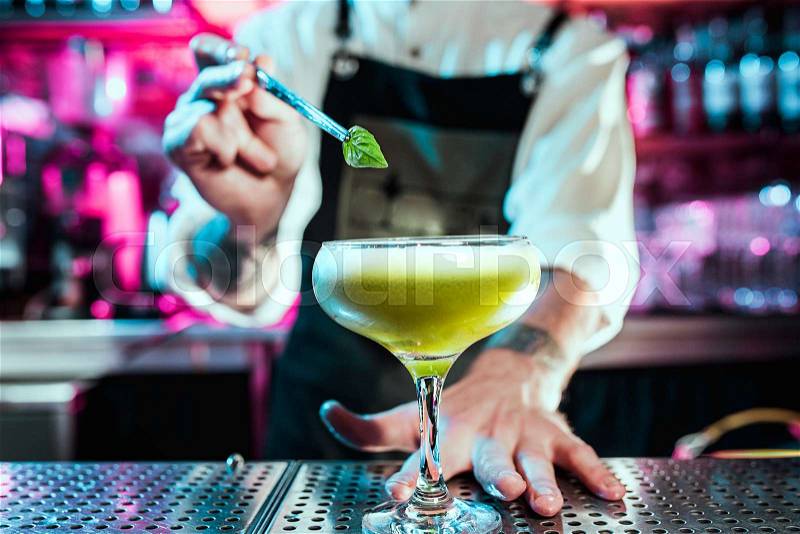 Expert barman is making cocktail at night club or bar. Glass of fiery cocktail on the bar counter against the background of bartenders hands with fire. Barman day ..., stock photo