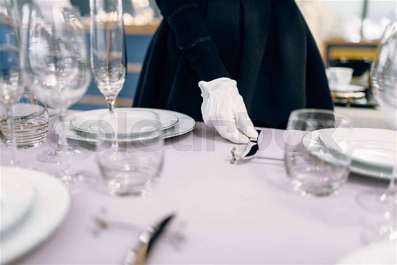 Waitress in gloves puts the knife, table setting. Serving service, festive dinner decoration, holiday dinnerware, stock photo