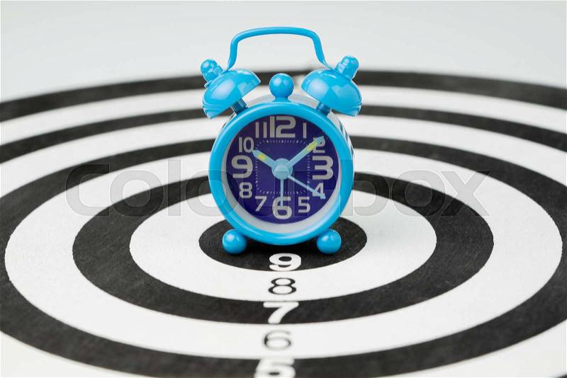 Small blue retro alarm clock at the center jackpot of black and white circle dartboard using as time, target or business goal with timeline concept, stock photo