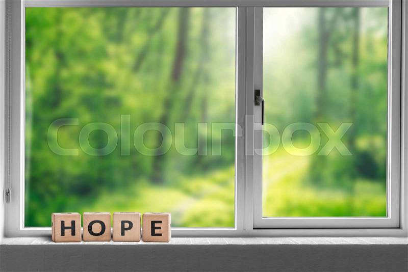 Hope sign in a window sill with a view to a green forest in sunlight, stock photo