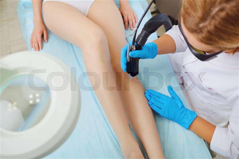Laser therapy. Hair removal on a womanâs legs by a laser in a beauty clinic, stock photo