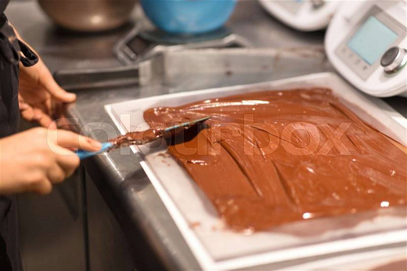 Production, cooking and people concept - confectioner making chocolate sweets at confectionery shop, stock photo