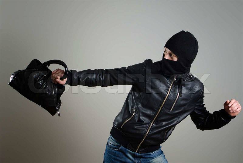 Portrait of running male burglar with a handbag, stock photo