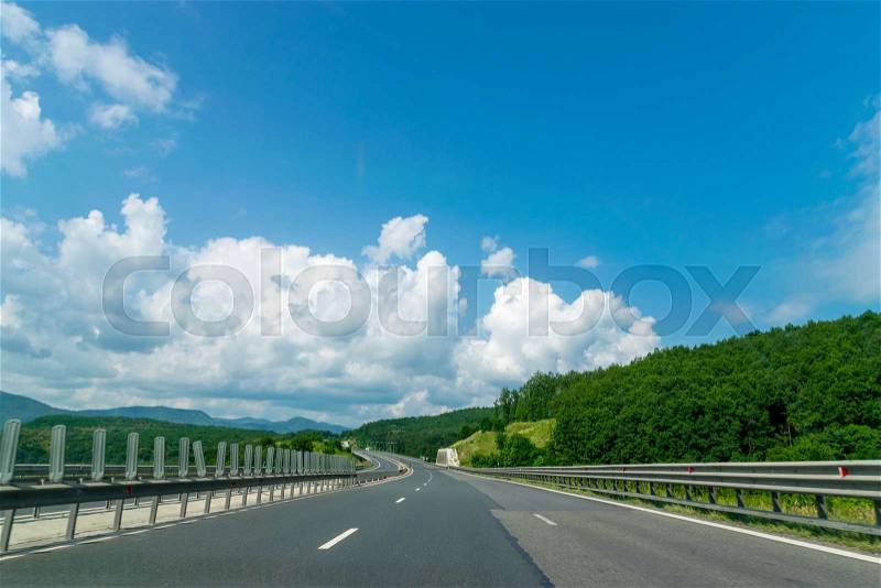 Asphalt highway and green nature landscape on a sunny day with blue sky in Romania, stock photo