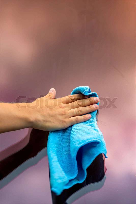 Male hand cleans the window glass from a microfiber cloth, close-up shot, stock photo