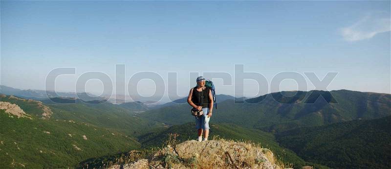 A person standing on the top of the mountain and looking far away ahead, stock photo