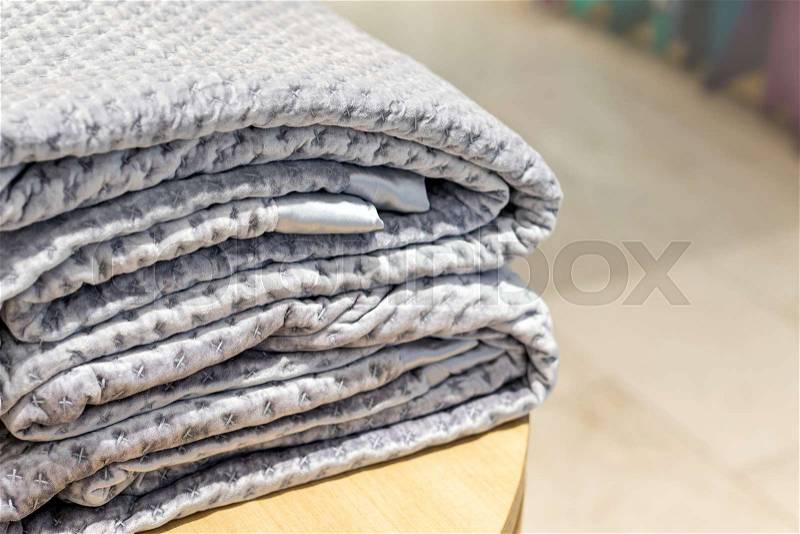 Folded velour blanket on wooden table at store, stock photo