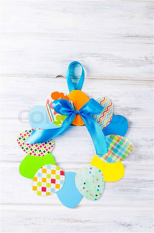 Craft of paper in the form of a wreath of colorful paper eggs on white wooden table. Child does crafts from paper. Idea project for kindergarten, Kids crafts. How ..., stock photo