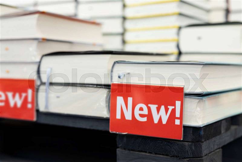 Bookstore shelf with pile of new books with red plate. New arrivals at bookshop. Presentation of book, stock photo