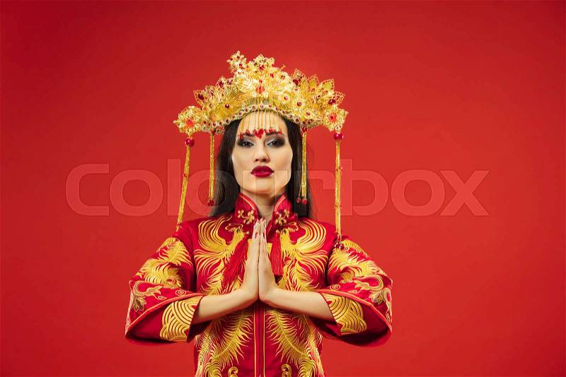 Chinese traditional graceful woman at studio over red background. Beautiful girl wearing national costume. Chinese New Year, elegance, grace, performer, performance, ..., stock photo