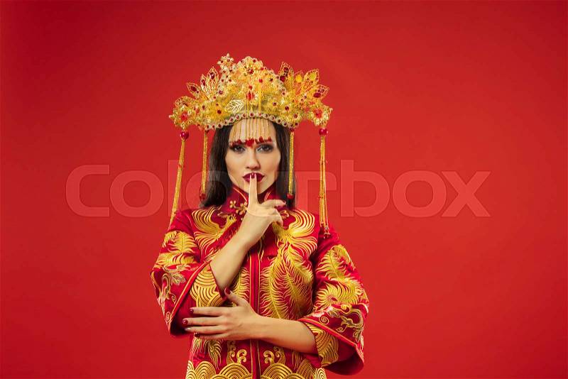 Chinese traditional graceful woman at studio over red background. Beautiful girl wearing national costume. Chinese New Year, elegance, grace, performer, performance, ..., stock photo