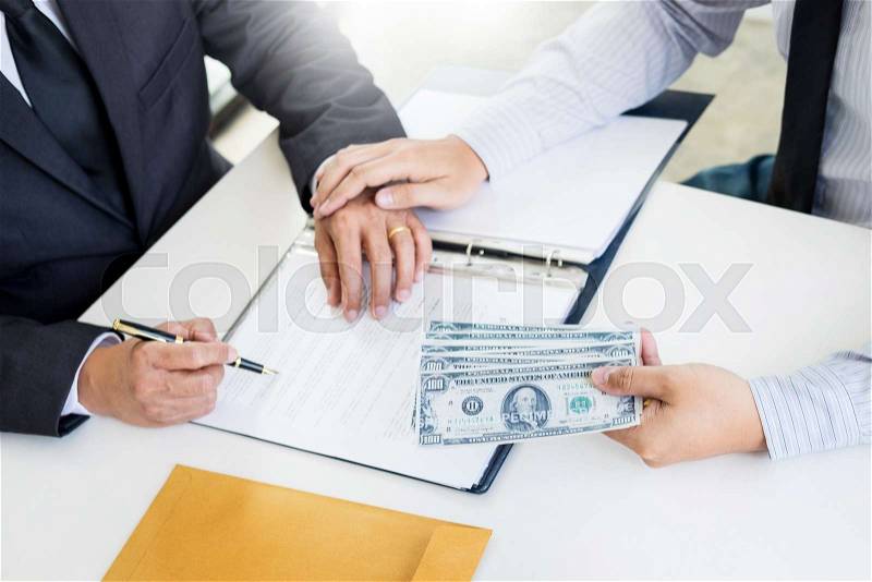 Businessman or politician taking bribe and Shaking Hands With Money in a suit, corruption trade exchange concept, stock photo