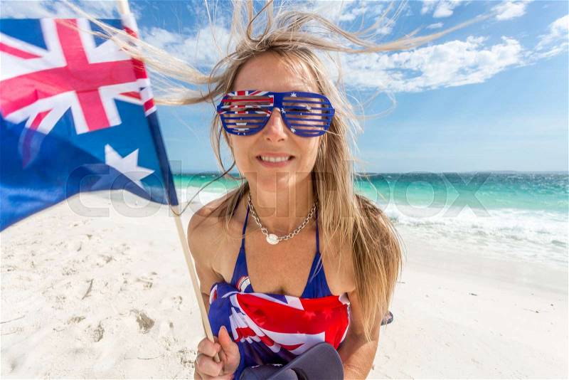 Australian culture a female Australian sports fan or supporter, or citizen celebrating Australia Day or other event. She has wind blown hair and is waving the ..., stock photo