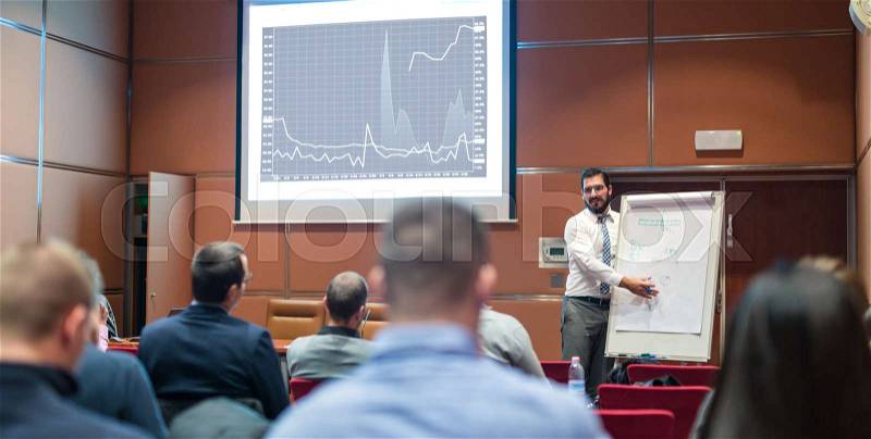 Public Speaker Giving a Talk at Business Meeting. Audience in the conference hall. Skilled coach answers questions of participants of business training. Business and ..., stock photo