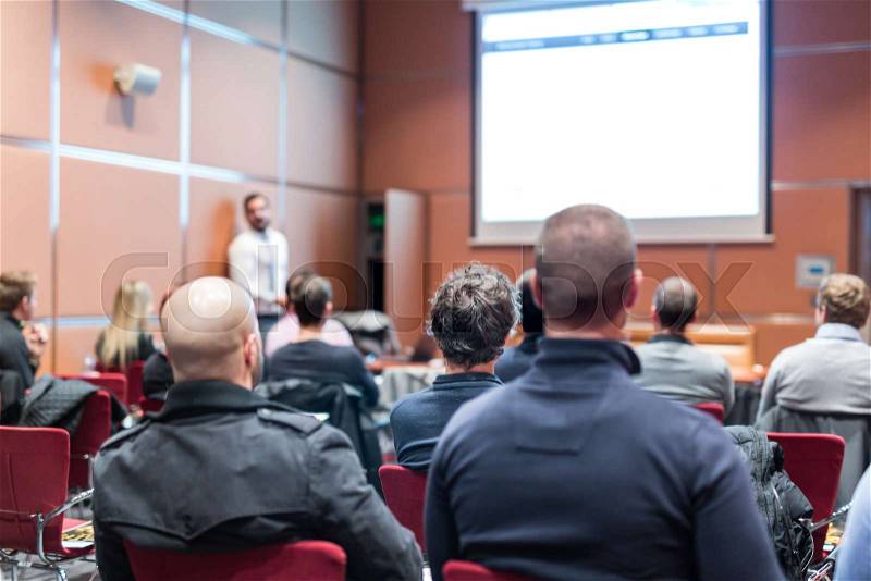 Public Speaker Giving a Talk at Business Meeting. Audience in the conference hall. Skilled coach answers questions of participants of business training. Business and ..., stock photo
