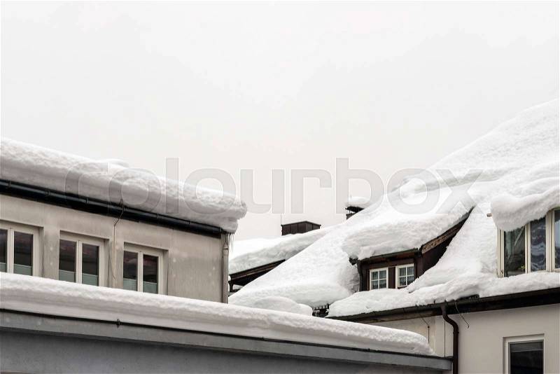Roof of building with window and thick snow layer in winter. Snowfall and blizzard weather forecast, stock photo