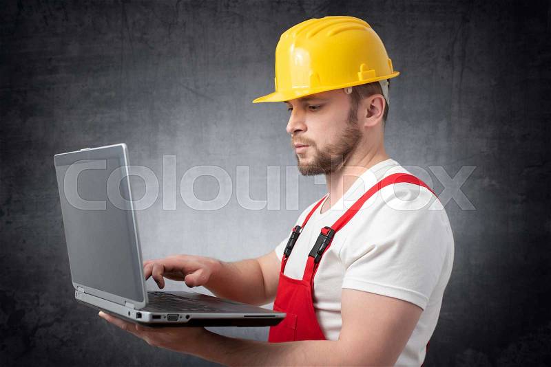 Construction worker with his laptop, stock photo