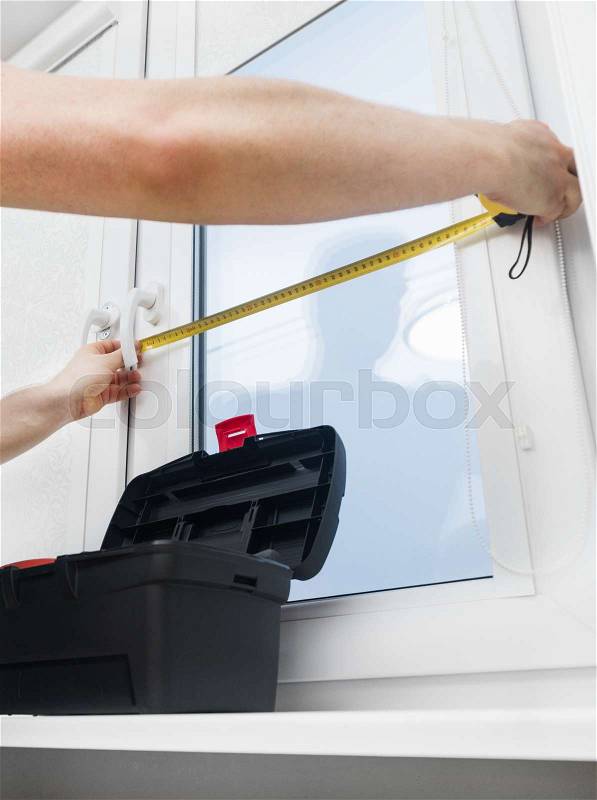 Handyman measuring window for cassette roller blinds, stock photo