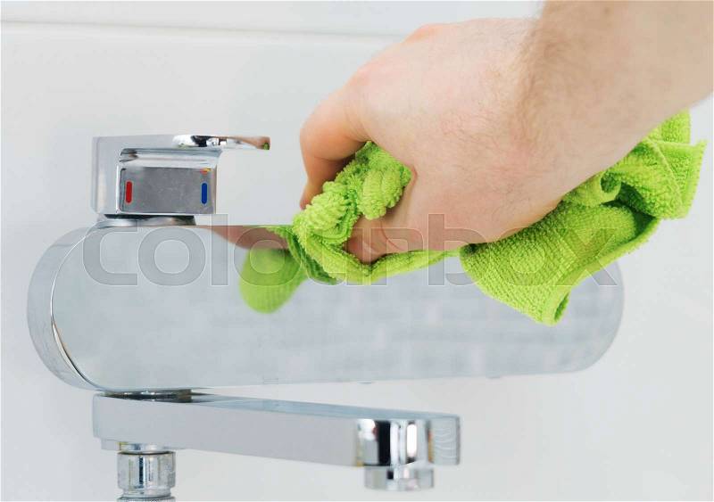 House cleaning. Man cleaning tap in bathroom, stock photo