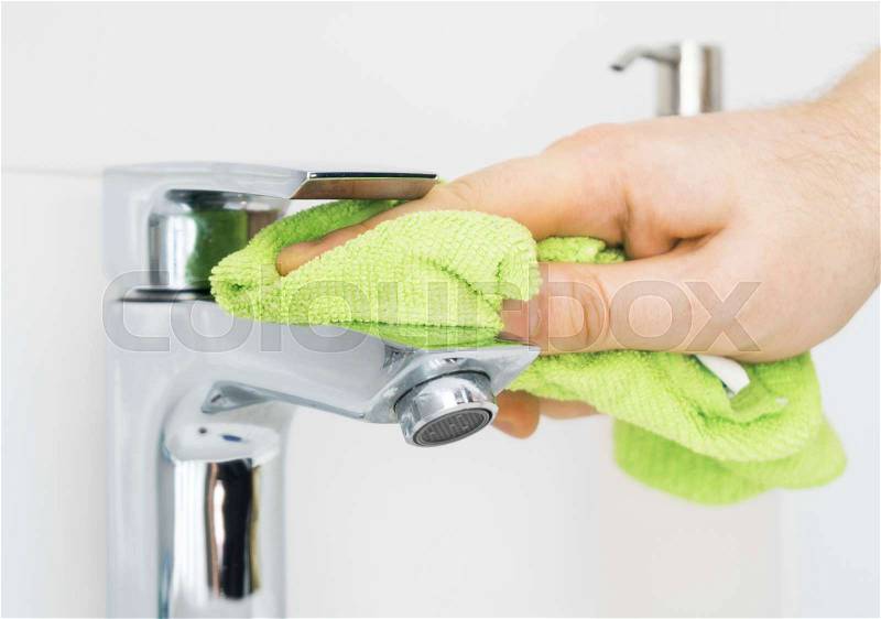 House cleaning. Man cleaning tap in bathroom, stock photo