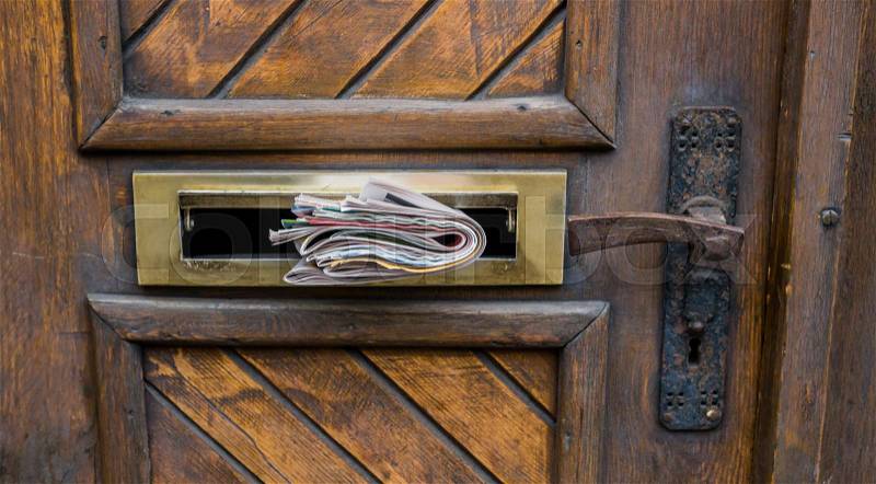 Front door with newspapers and direct marketing in the letter slot, stock photo