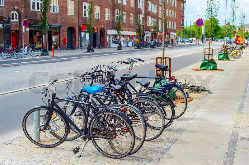 Copenhagen city street with bicycles parking at sidewalk, focus on foreground, Denmark, stock photo