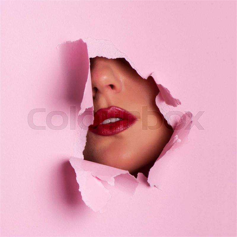 View of bright lips through hole in pink paper background. Square crop. Make up artist, beauty cosmetics sale. Spring, woman day concept. Beauty salon advertising ..., stock photo