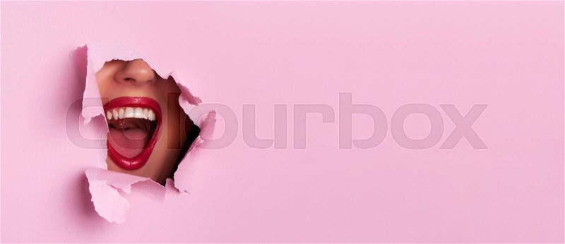 Bright red lips through torn pink paper background. Surprised girl, emotions. Make up artist, beauty concept. Ready to party. Cosmetics sale. Beauty salon ..., stock photo