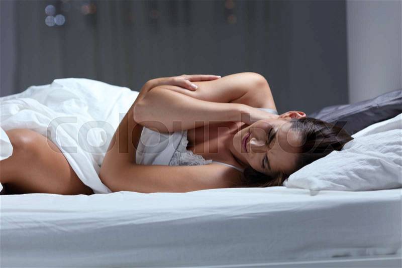 Woman complaining suffering neck ache sleeping with a bad pillow on a bed at home, stock photo