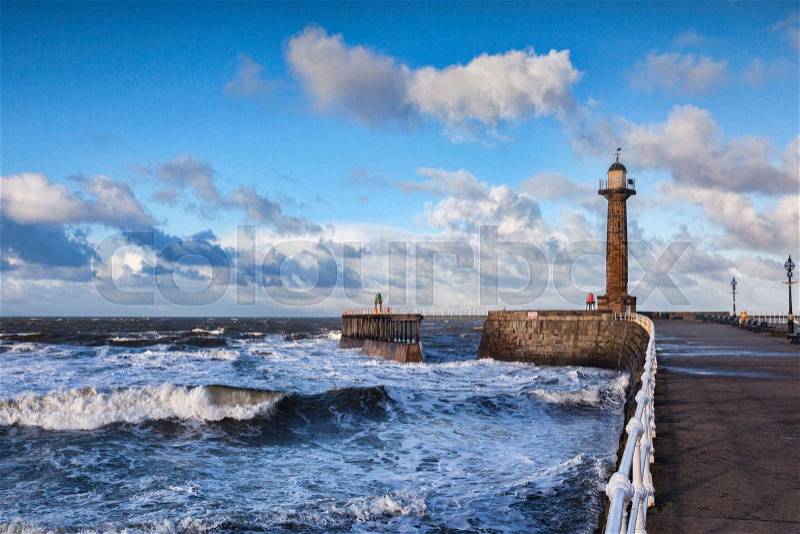 Wind and a rising tide produce rough seas at the entrance to Whitby Harbour in North Yorkshire, on a bright winter afternoon, stock photo