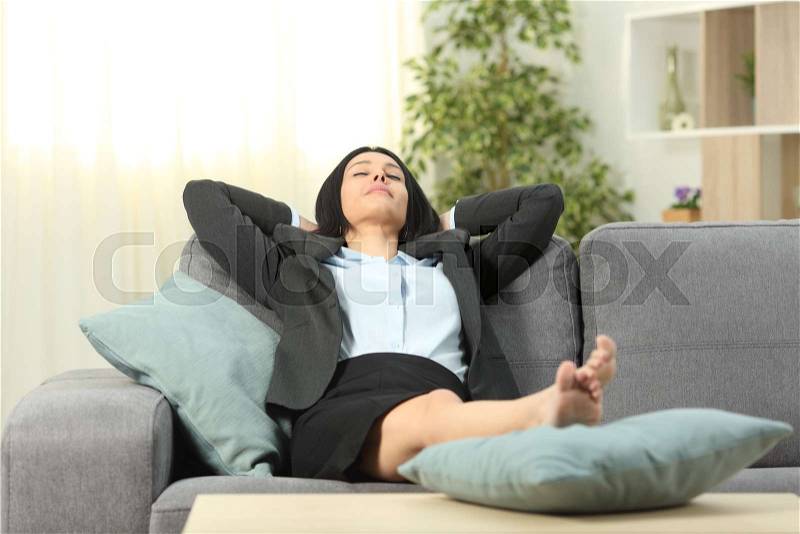Tired office worker resting sitting on a couch at home after work, stock photo