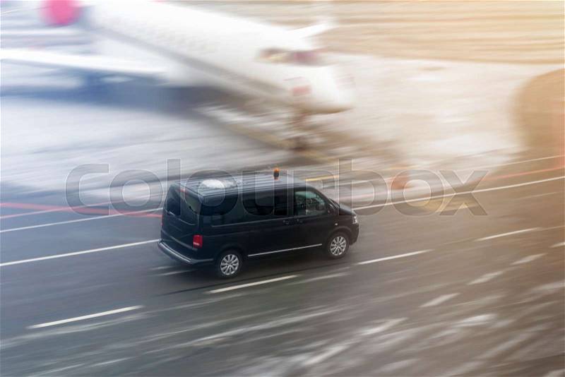Black VIP service van running on airport taxiway with blurred private jet on background. Business class service at airport. Security intelligence agency hurrying at ..., stock photo