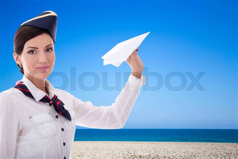 Summer and travel concept - beautiful stewardess with paper plane over beach background, stock photo
