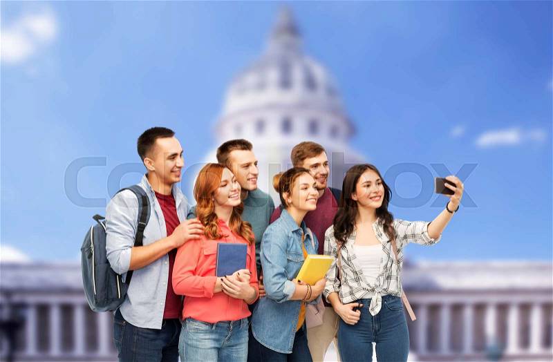 Education, high school and technology concept - group of smiling students with books taking selfie by smartphone over capitol building background, stock photo
