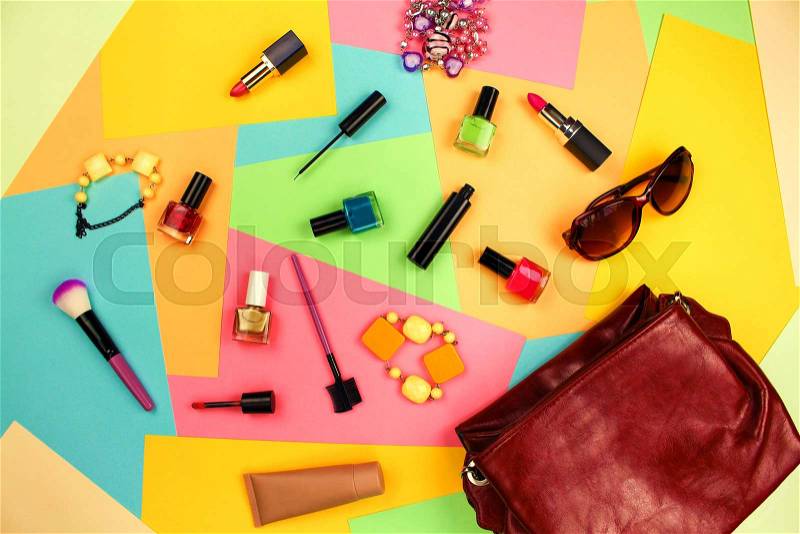 Things from open lady purse. Cosmetics and women\'s accessories fell out of red handbag on colourful background. Top view. Flat lay, stock photo