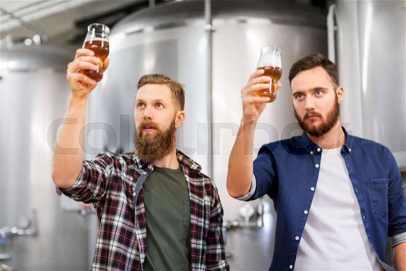 Alcohol production, manufacture, business and people concept - men drinking and testing craft beer at brewery, stock photo