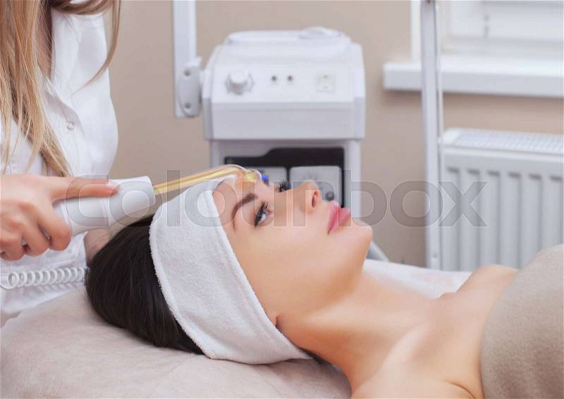 The doctor-cosmetologist makes the Microcurrent therapy procedure of a beautiful, young woman in a beauty salon.Cosmetology and professional skin care, stock photo