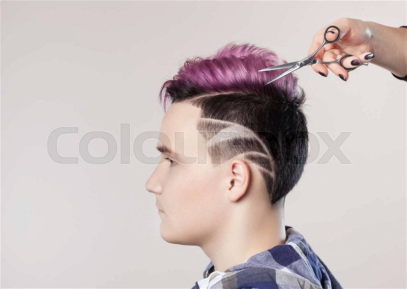 Hairdresser cuts hair. Portrait of a beautiful young teenager with a beautiful creative hairstyle, hair painted in pink, stock photo