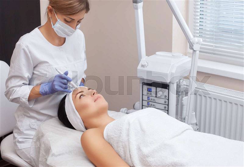 The doctor-cosmetologist makes the procedure treatment of Couperose of the facial skin of a beautiful, young woman in a beauty salon.Cosmetology and professional ..., stock photo