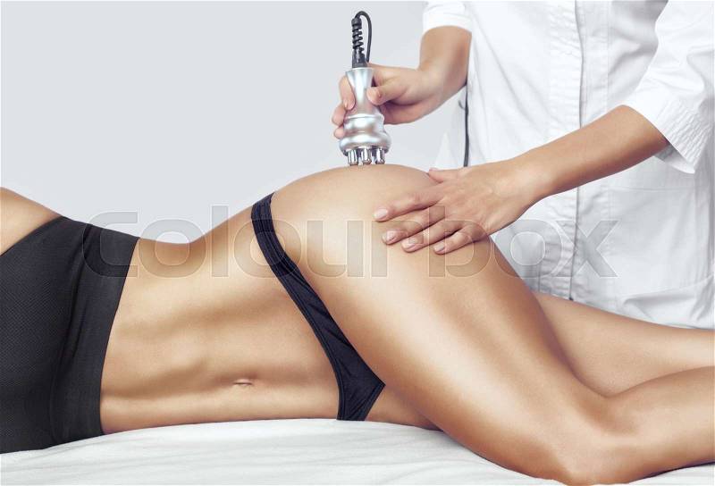 The doctor does the Rf lifting procedure on the legs, buttocks and hips of a woman in a beauty parlor. Treatment of overweight and flabby skin, stock photo