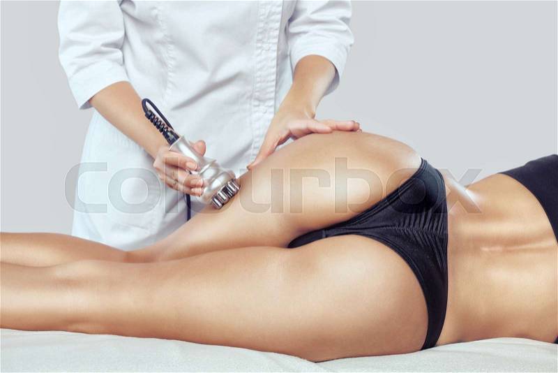 The doctor does the Rf lifting procedure on the legs, buttocks, thighs and hips of a woman in a beauty parlor. Treatment of overweight and flabby skin, stock photo