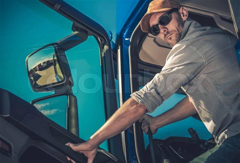 Transportation Industry. Semi Truck Driving. Caucasian Driver in His 30s is About to Hit the Road with Heavy Load Cargo, stock photo