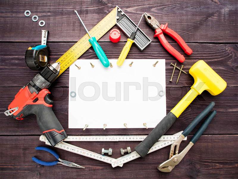 The tool building on the wooden background around the white sheet of paper, stock photo