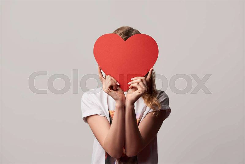 Girl with obscure face and empty paper cut heart card isolated on grey, stock photo