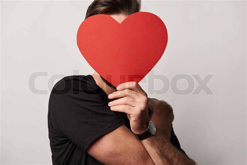Man in black with obscure face and empty paper cut heart card , stock photo