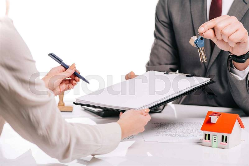 Cropped view of mortgage broker and woman making deal and holding keys isolated on white, mortgage concept, stock photo